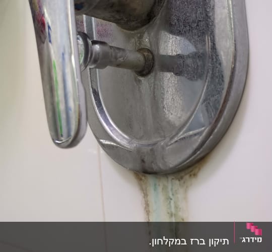 ברז מתכת עם חלודה ונזילה על קיר אריחים